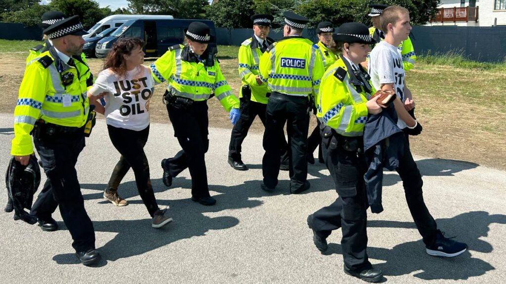 Manifestantes de Just Stop Oil son escoltados por la policía en el hoyo 17 después de que lanzaron un material naranja al campo en el Abierto Británico | AP